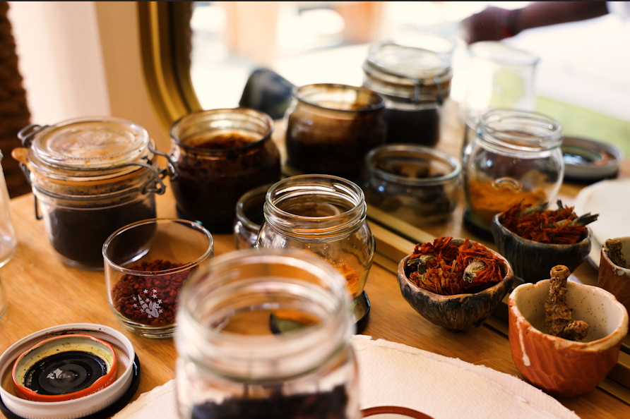 Several jars all filled with brown materials and water and rust colored pigments, all used for painting.